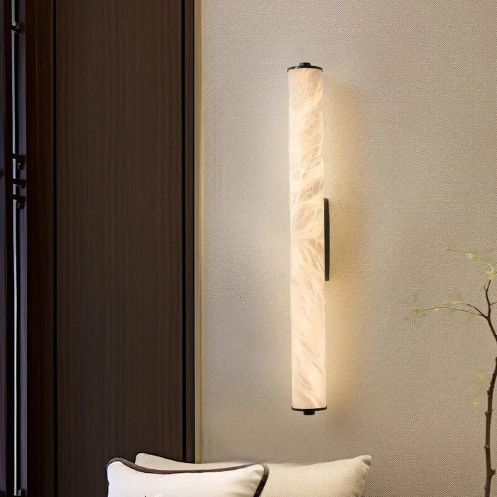 Calacatta marble wall light with black finish glowing warm white in a modern bedroom