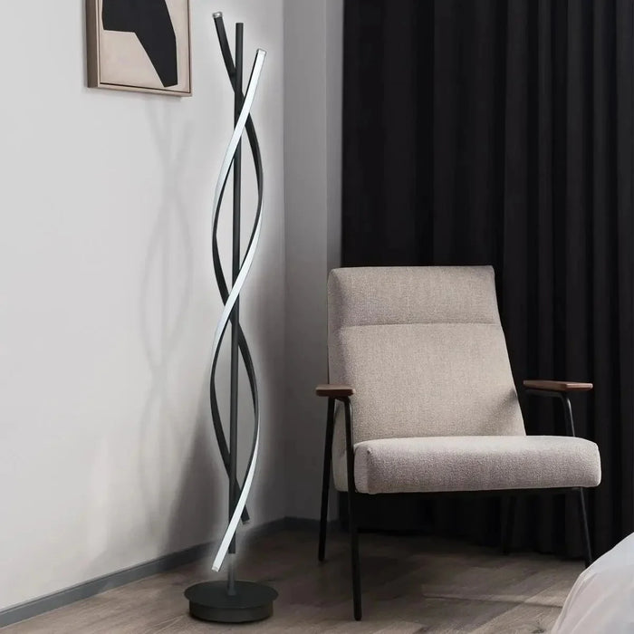 The Helix Aura Floor Lamp black spiral LED lamp beside an armchair