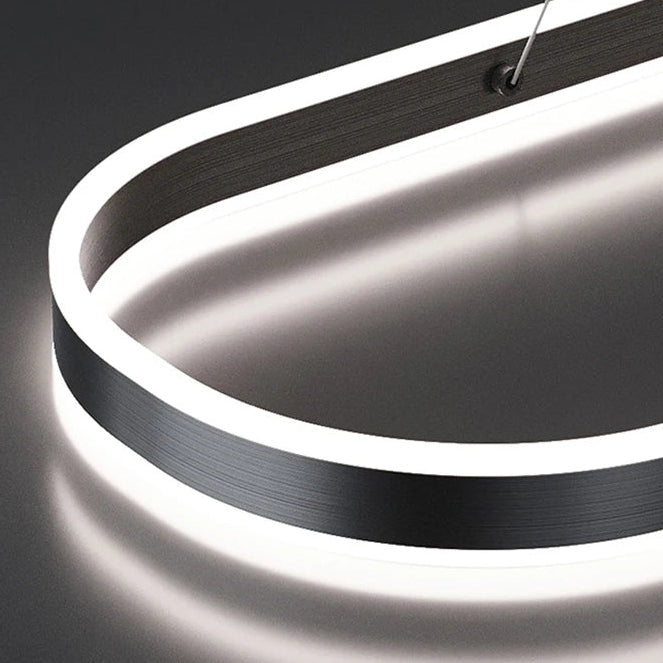A close-up of a modern LED linear pendant light with a brushed black metal frame and bright white illuminated edge, shown against a dark gray background with the KAGU brand logo in the top left.