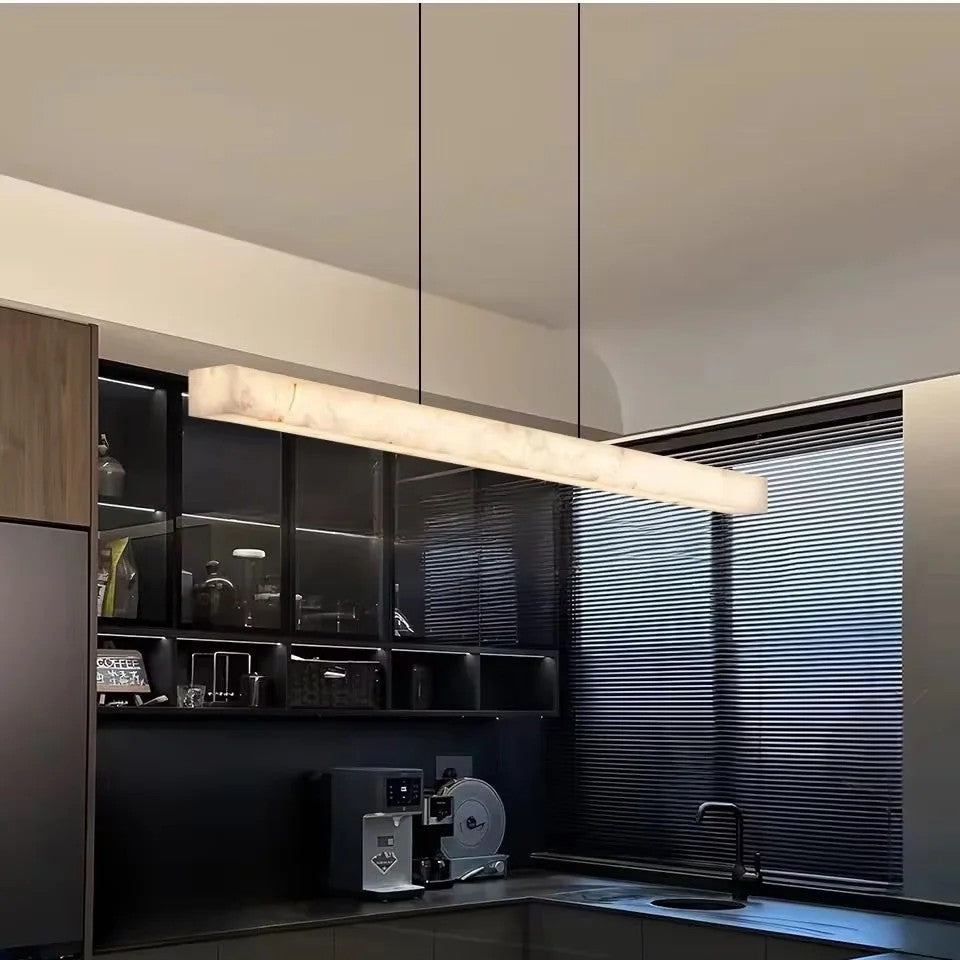 Alabastro linear pendant light above a dining table in a modern dark kitchen