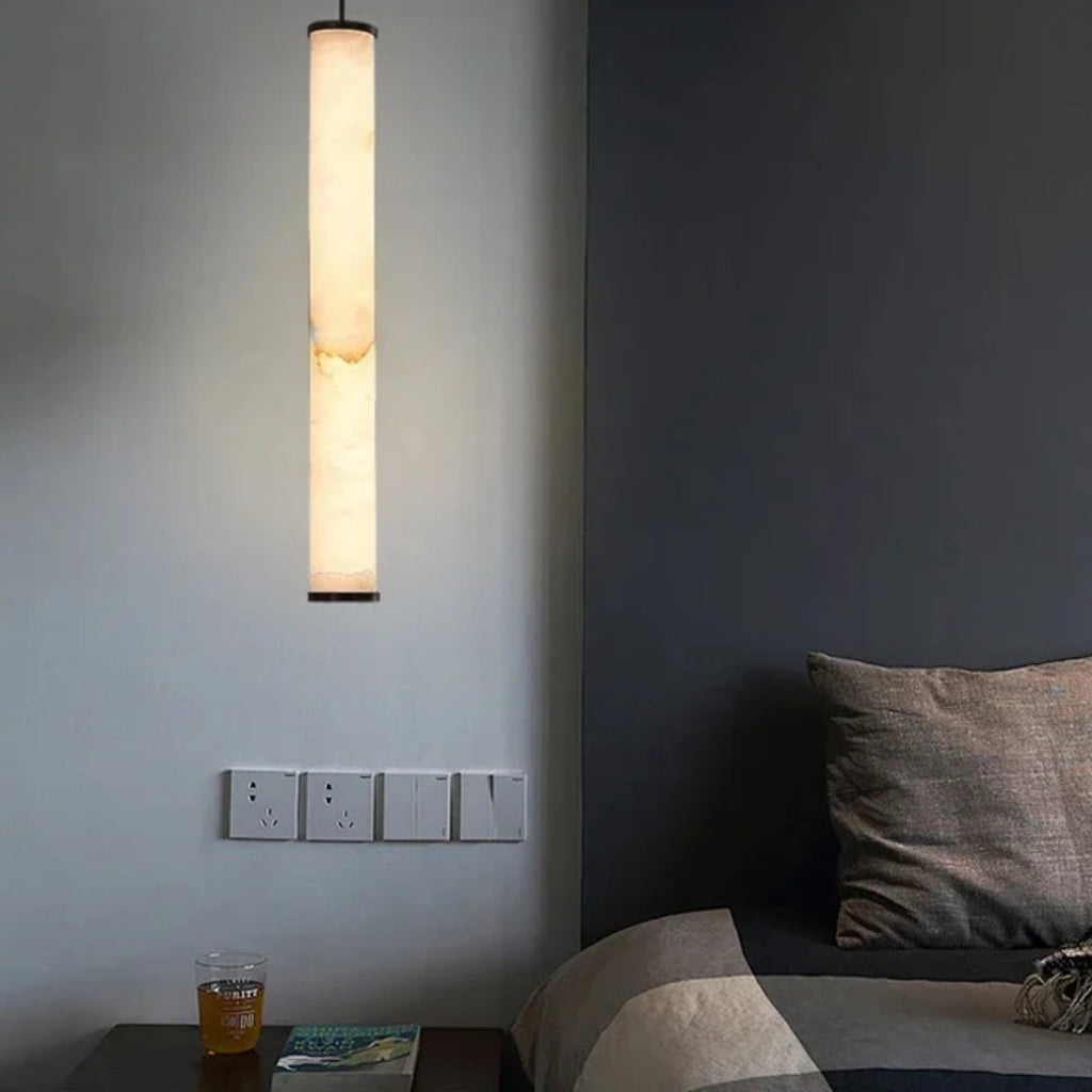 Slim Calacatta natural stone pendant light hanging beside a bed in a modern grey bedroom