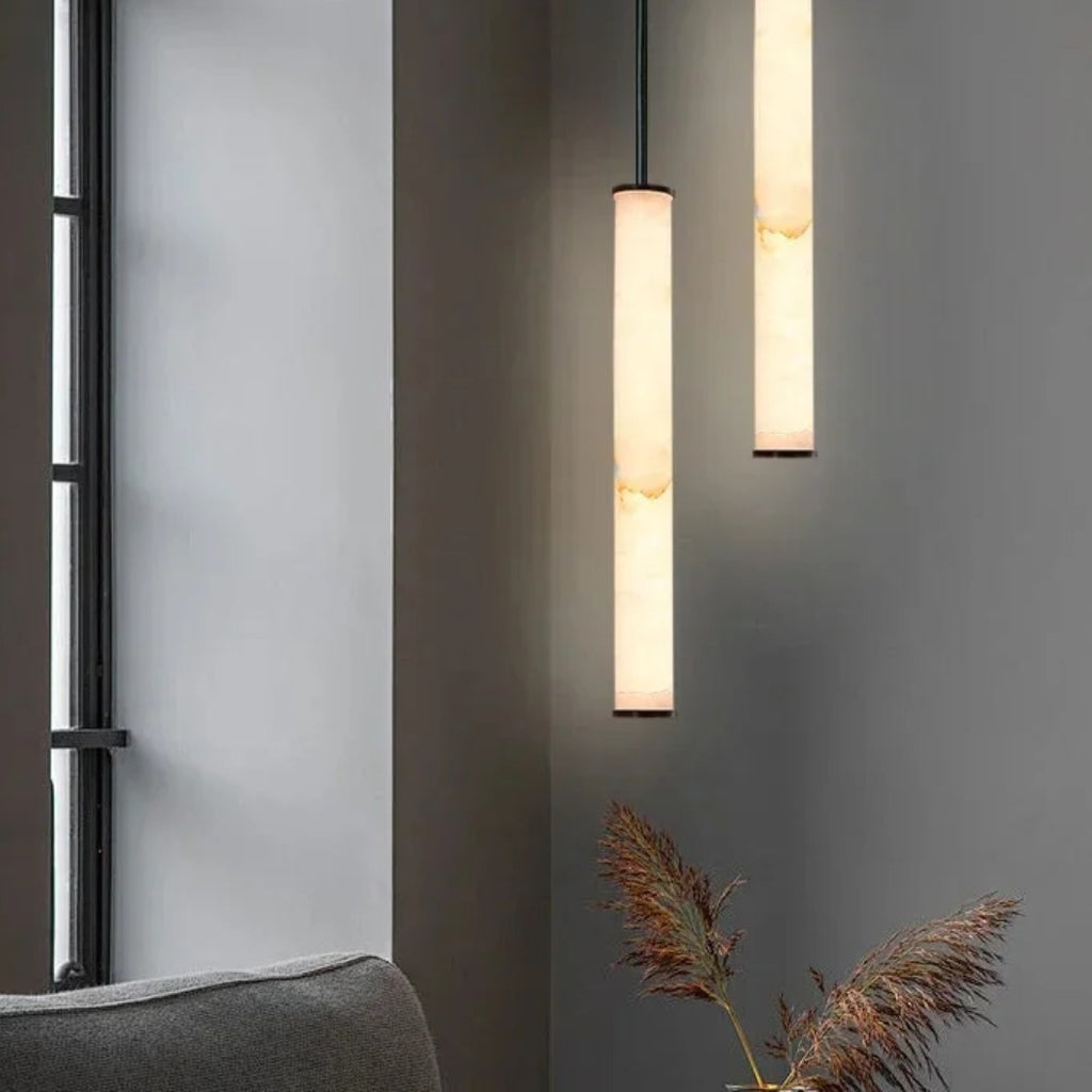 Pair of Calacatta marble pendant lights hung at staggered heights in a modern living room
