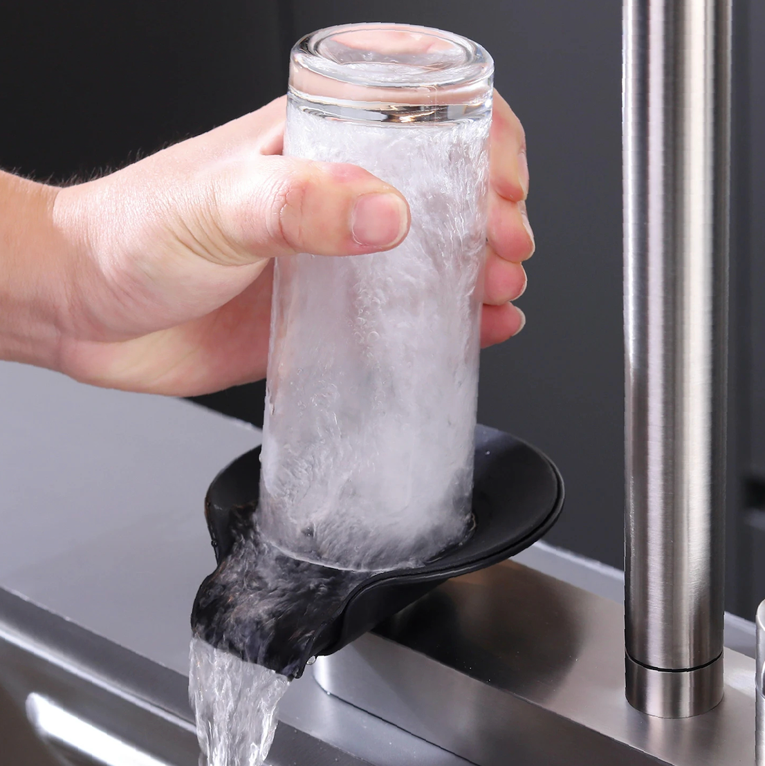 The Camden Pull-Out Kitchen Mixer Tap in Matte Black filling a glass with water at the sink